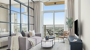 Ein modernes Wohnzimmer mit einem grauen Sofa, einem Couchtisch und einem Fernseher auf einem schwarzen Standfuß.