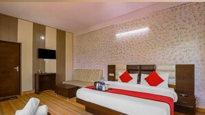 A hotel room with a large bed, a TV mounted on the wall, and a wooden floor. - The Neer Budha (Narendranagar)