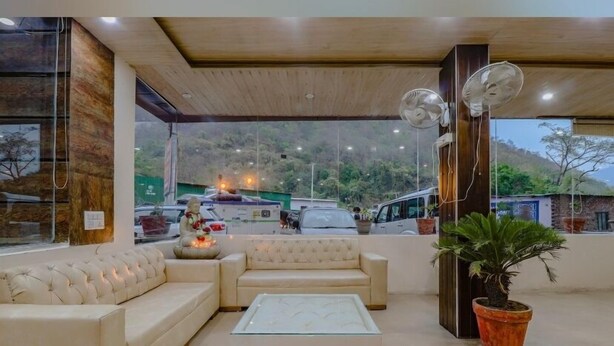 A modern living room with a sofa set, a glass coffee table, and a potted plant. - The Neer Budha (Narendranagar)