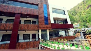 A multi-story building with a modern design, featuring large windows and a prominent vertical wooden panel. - The Neer Budha (Narendranagar)