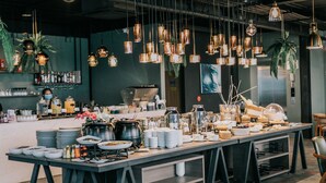 A buffet setup with multiple serving stations, hanging pendant lights, and a bar area in the background. - Eco Cozy Beachfront Resort Chaam (Cha-am)