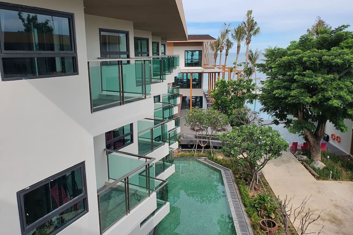 Un bâtiment moderne doté de nombreux balcons, d’une piscine et d’une végétation luxuriante.