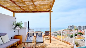 Une terrasse en bois avec une piscine, des chaises longues, un canapé et une plante en pot.