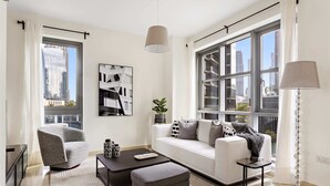 A modern living room with a sofa, armchair, and coffee table, large windows with city views, and a floor lamp. - Silkhaus Standpoint, Downtown Dubai (Dubai)