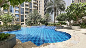 A swimming pool with a blue mosaic pattern, surrounded by palm trees and a modern building in the background. - Silkhaus Standpoint, Downtown Dubai (Dubai)
