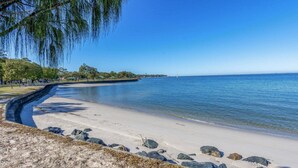 A beach with clear blue water, a sandy shore, and a stone wall. - Executive Unit in the Treetops (BONGAREE)