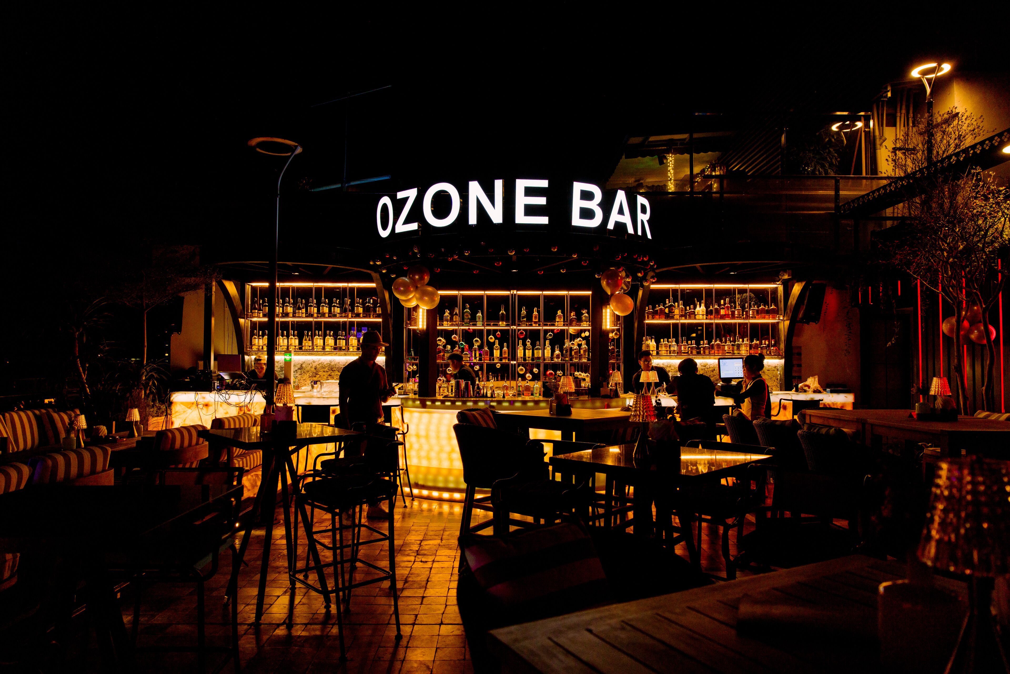 Eine Bar mit einem neonbeleuchteten Schild mit der Aufschrift „OZONE BAR“ und einer Auswahl an Flaschenregalen.