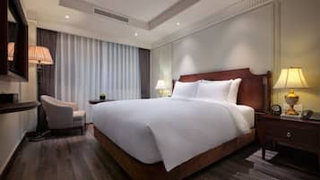 Une chambre d’hôtel avec un grand lit, un bureau avec une lampe, une chaise et une table de chevet avec une lampe.