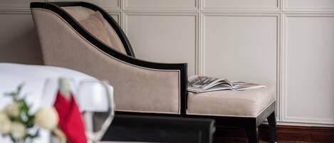 A modern room with a sofa, a small table with a vase and a red cloth, and a magazine on the sofa.