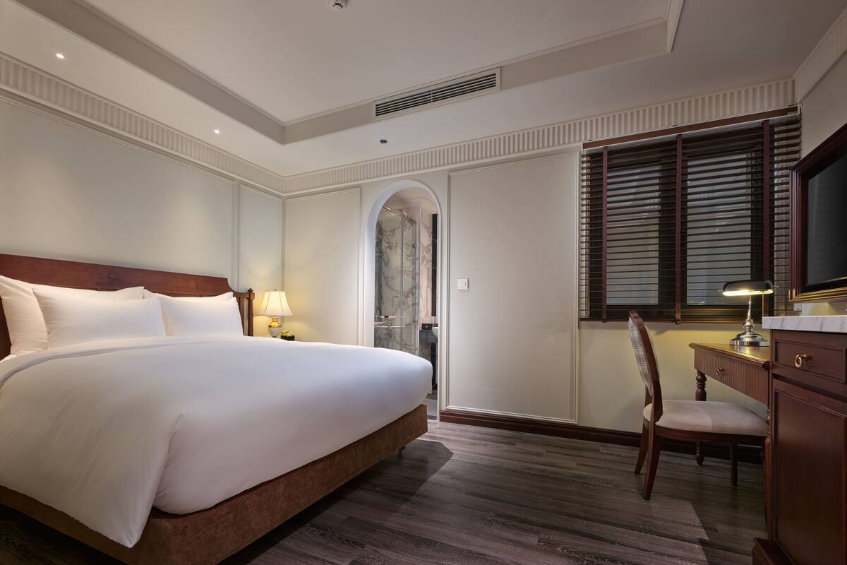 Une chambre d’hôtel avec un grand lit, un bureau avec une chaise, une télévision et un espace douche.