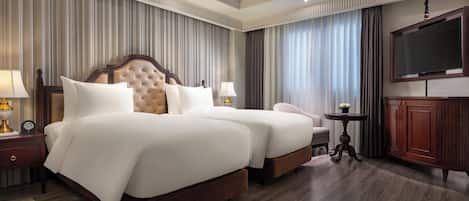 A hotel room with a large bed, two bedside tables with lamps, a TV, and a wooden cabinet.