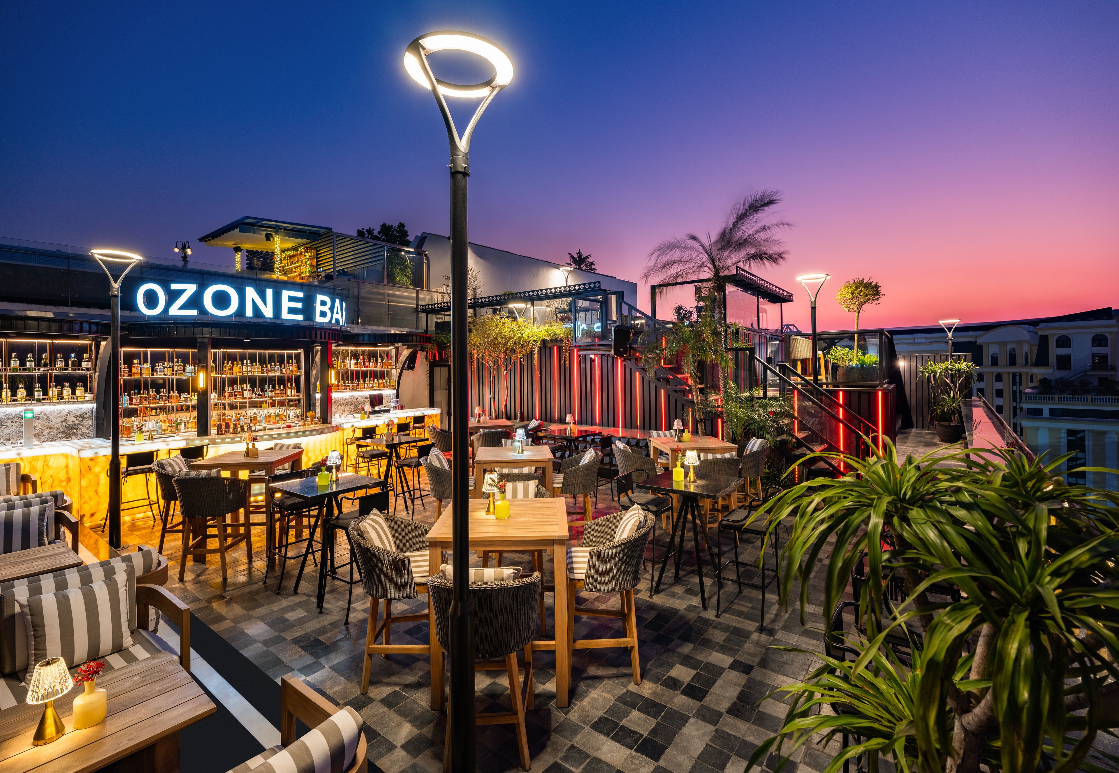 Un área de bar al aire libre con suelo a cuadros, mostradores y asientos.