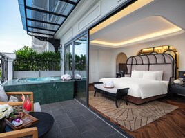 A modern hotel room with a large bed, a glass-enclosed jacuzzi, and a view of the outdoors.