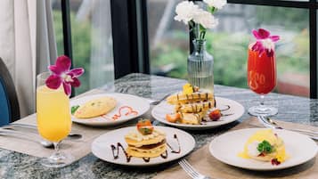 A table with various breakfast dishes, including waffles, pancakes, and a glass of orange juice.