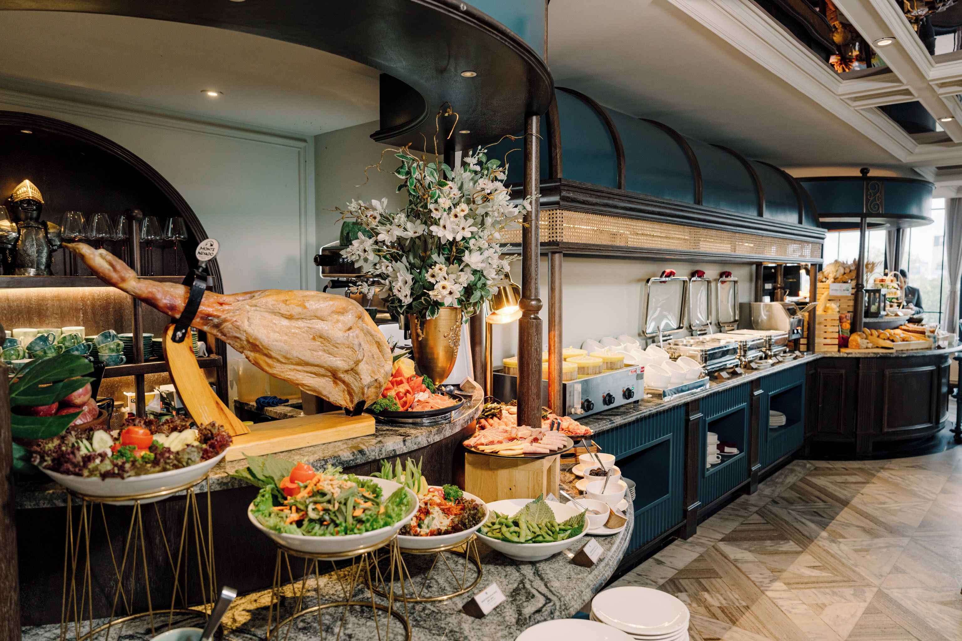A buffet setup with various food items, a large roasted meat centerpiece, and a kitchen area in the background.
