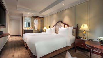 Una cama grande y bien hecha con sábanas blancas, cabecera de madera y mesita de noche con lámpara.