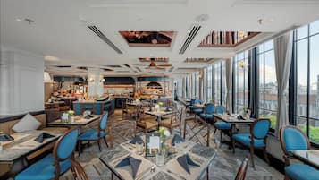 A spacious restaurant with high ceilings, large windows, and a mix of seating arrangements including tables and booths.
