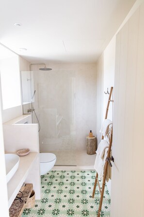 Een moderne badkamer met douche, toilet en wastafel.