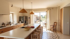 Eine moderne Küche mit einer großen Kochinsel, Holzschränken und einem Essbereich mit Tisch und Stühlen.