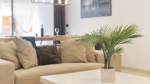 Een moderne woonkamer met een beige bank, een bijzettafeltje en een potplant.