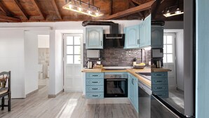Een keuken met lichtblauwe kastjes, een zwarte oven en een houten plafond.
