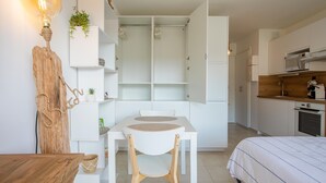 Una habitación compacta y moderna con una mesa de comedor, una silla, una cama y una kitchenette.