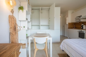Une pièce compacte et moderne, comprenant une table à manger, une chaise, un lit et un coin cuisine.