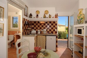 A compact kitchen with a checkered backsplash, a small refrigerator, and a dining area with a table and chairs.