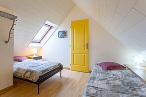 Un dormitorio con una cama, una mesita de noche, una lámpara, una ventana y una puerta.