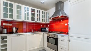 A kitchen with white cabinets, a red backsplash, stainless steel appliances, and a gas stove. - Holiday Home 'Chez Fanch' with Private Terrace, Private Garden and Wi-Fi (Camaret-sur-Mer)