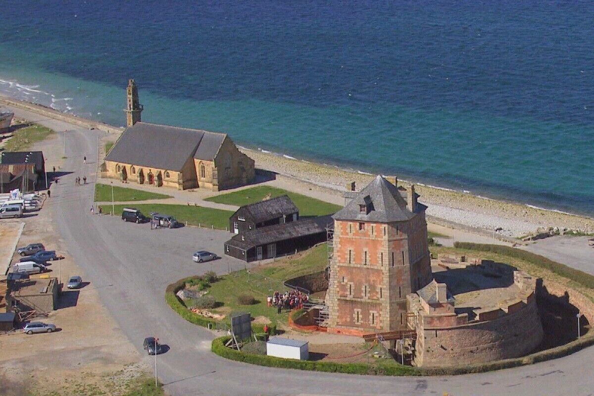 A coastal historical site with a prominent tower, a church, and a fortified structure.