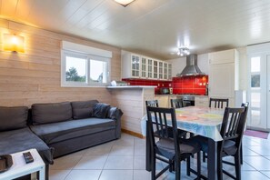 Una cocina moderna con armarios blancos, un salpicadero rojo y un comedor con mesa y sillas.