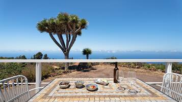 Une table avec de la nourriture et des boissons, une bouteille, et une vue sur l’océan.