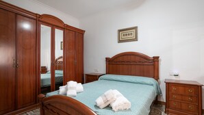 Un dormitorio con una cama de madera, un armario, una mesita de noche y un espejo.