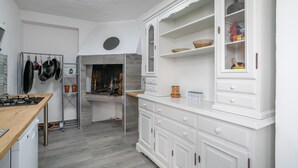Una cocina con armarios blancos, una estufa y un colgador para ollas.