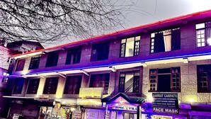 A multi-story building with various shops on the ground floor, including a face mask store and a carpet cleaning service. - Amar Villa Manali (Manali)