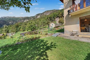 Il s’agit d’une propriété résidentielle dotée d’un jardin, d’un balcon aménagé avec du mobilier d’extérieur et offrant une vue sur un paysage montagneux.