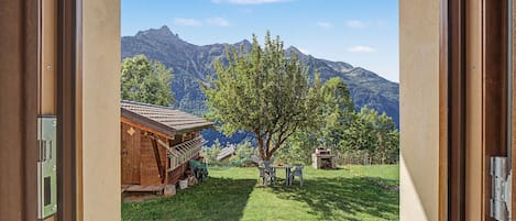 Une cabane en bois avec vue sur la montagne, une cour gazonnée et un hamac.