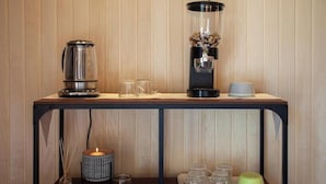 A wooden wall with a metal shelf holding a coffee maker, a glass carafe, and a candle. Below, there are glass jars and a candle holder. - Casa SOLE, swimming pool and wellness (Castiglione Tinella)