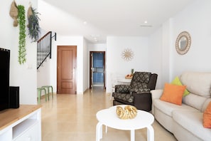 A living room with a sofa, a coffee table, a TV, and a staircase.