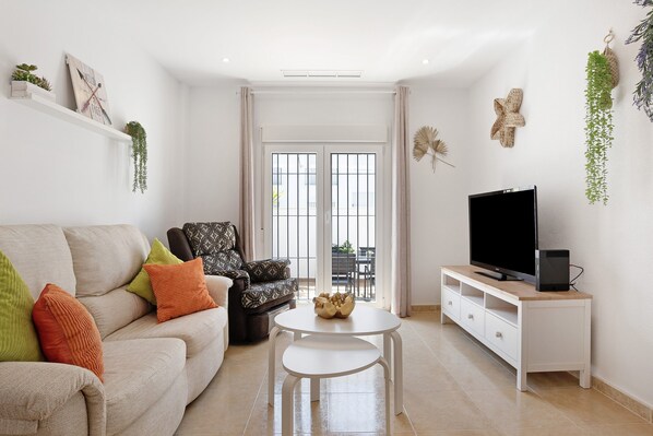A living room with a sofa, armchair, TV, and a small table.