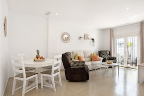A living room with a white dining table, chairs, a sofa, and a recliner.