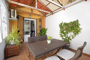 Een terras met een tafel en stoelen, een potplant en een aan de muur bevestigde plant.