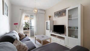 Una sala de estar moderna con sofá, televisor y vitrina de vidrio.