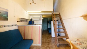Una cocina pequeña con mostrador de madera, un sofá azul, una escalera y una escalera que sube a un nivel superior.