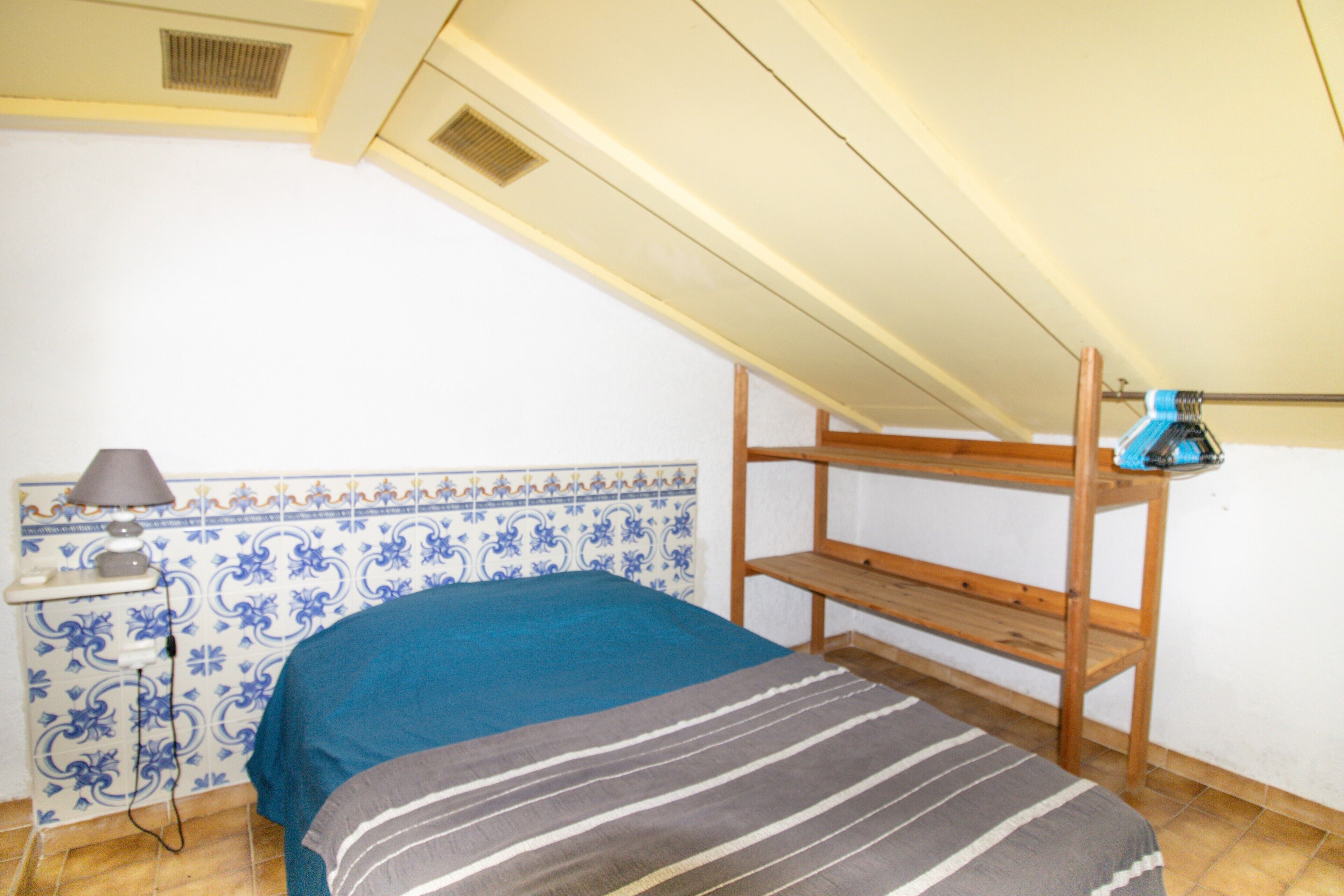 Ein Zimmer mit einem Etagenbett, einem Nachttisch mit Lampe und einer Wand mit blauen und weißen Fliesen.