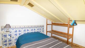 Ein Zimmer mit einem Etagenbett, einem Nachttisch mit Lampe und einer Wand mit blauen und weißen Fliesen.