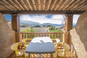 A covered outdoor area with a table and chairs, a view of mountains and a body of water.