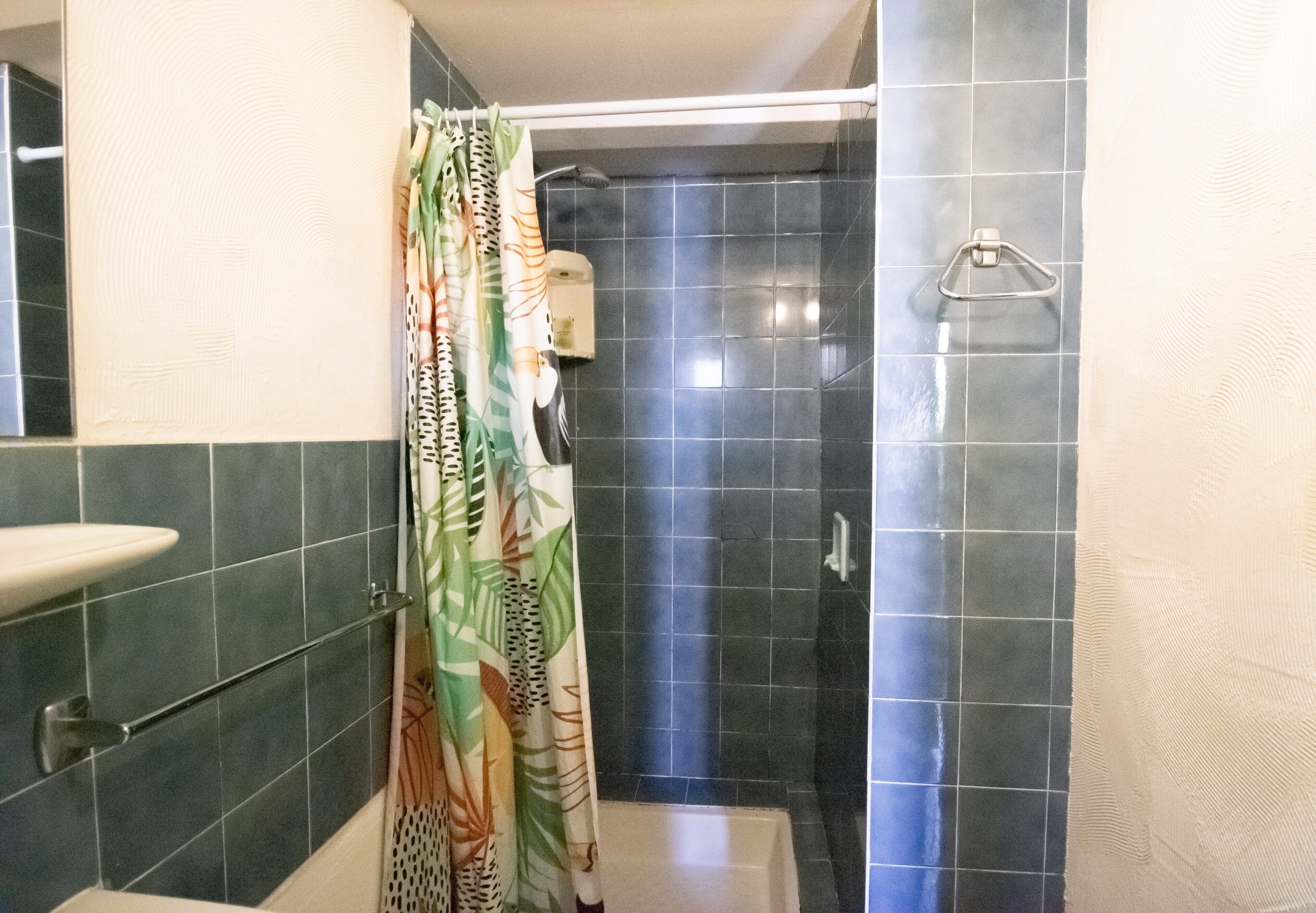 Une salle de bain avec une douche, un lavabo et un porte-serviettes.