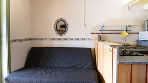 A compact room with a bed, a small kitchenette, a mirror, and a tiled backsplash. - "Le Quattru" Apartment with Sea View, Wi-Fi, and Air Conditioning (Appietto)